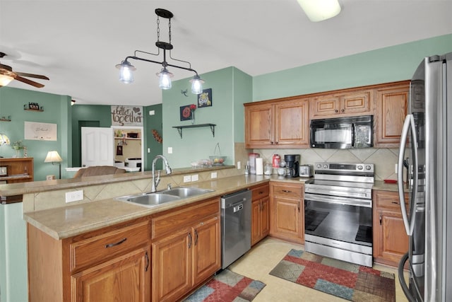 kitchen featuring stainless steel appliances, sink, kitchen peninsula, backsplash, and pendant lighting