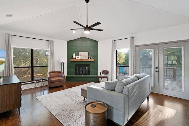 living room featuring dark wood-type flooring, lofted ceiling, baseboard heating, ceiling fan, and a fireplace