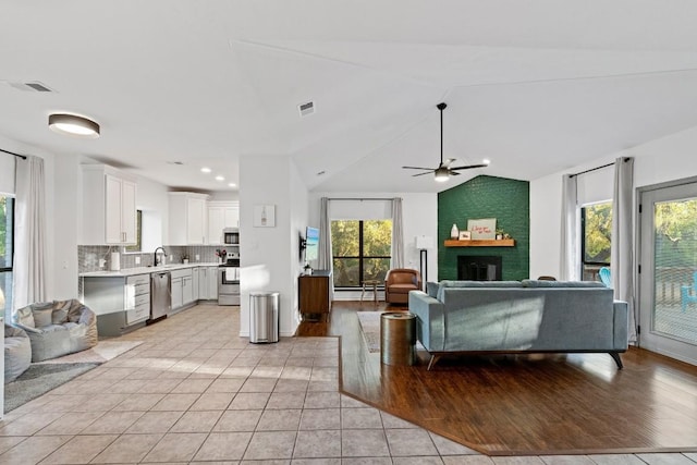 tiled living room with ceiling fan, lofted ceiling, a fireplace, and a baseboard radiator