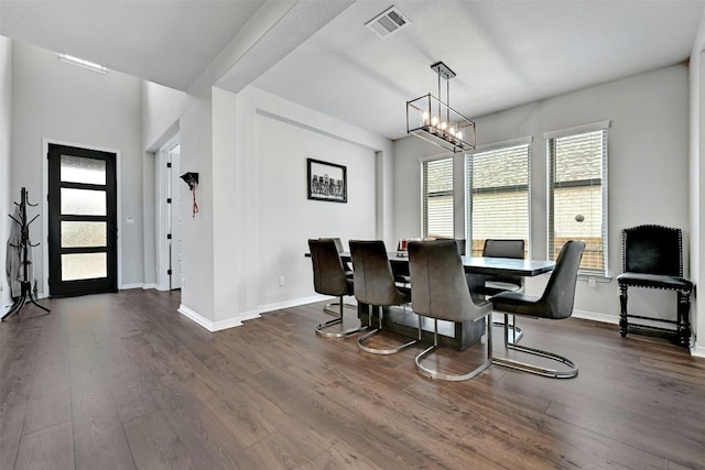 dining space with dark hardwood / wood-style flooring and a chandelier