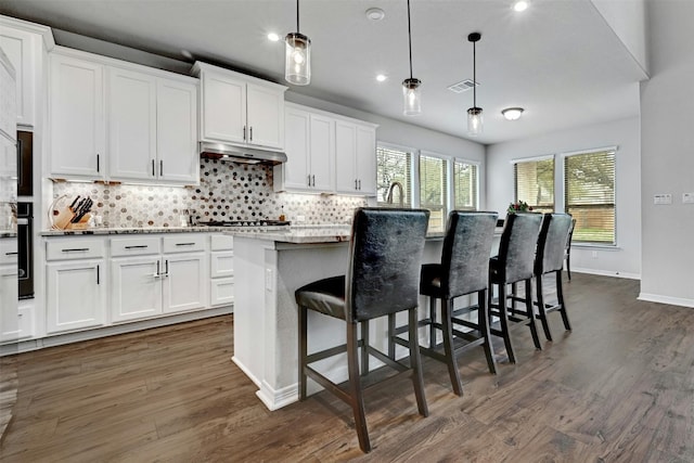 kitchen with white cabinets, dark wood-type flooring, decorative light fixtures, and a kitchen island