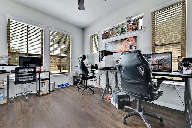 home office with dark wood-type flooring, ceiling fan, and a healthy amount of sunlight