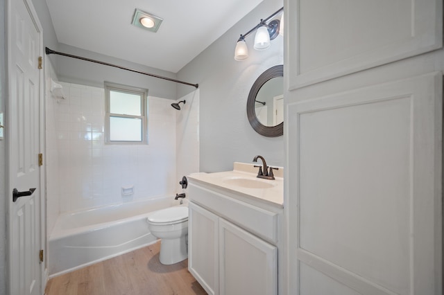 full bathroom with tiled shower / bath combo, toilet, vanity, and hardwood / wood-style flooring