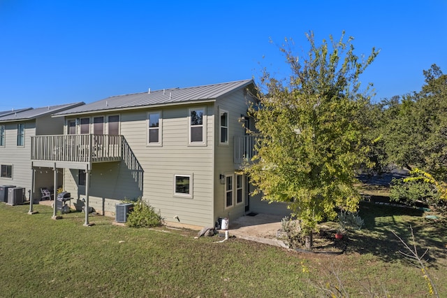 rear view of property featuring a lawn, a balcony, and central AC unit