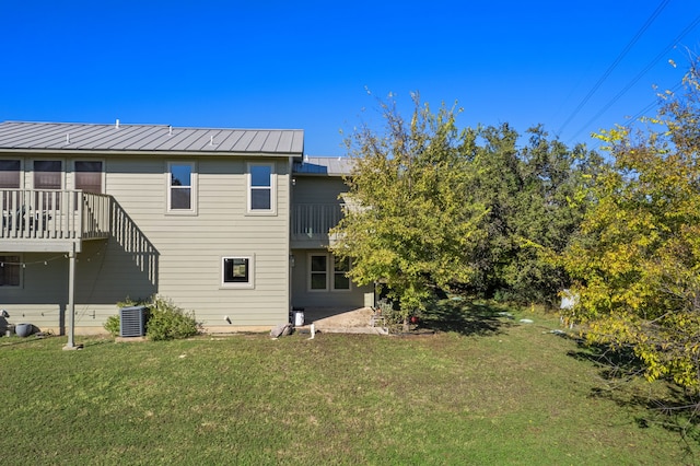 back of house with central AC unit and a yard