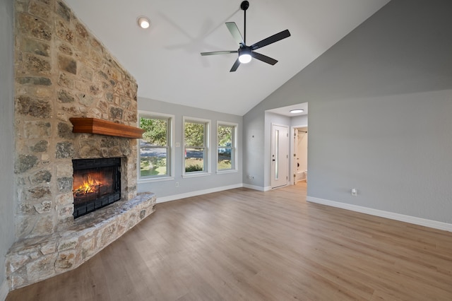 unfurnished living room featuring high vaulted ceiling, ceiling fan, light hardwood / wood-style flooring, and a stone fireplace