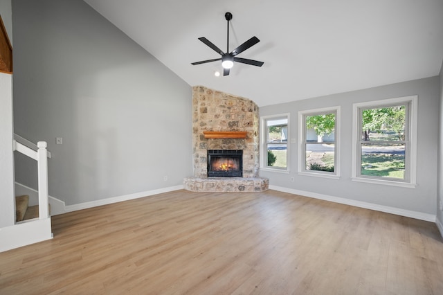 unfurnished living room with a fireplace, light wood-type flooring, ceiling fan, and vaulted ceiling