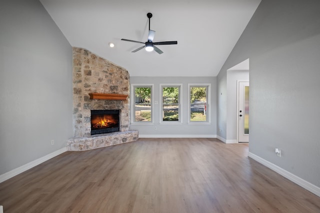 unfurnished living room with hardwood / wood-style flooring, high vaulted ceiling, ceiling fan, and a stone fireplace