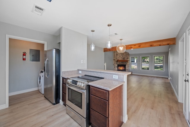 kitchen with independent washer and dryer, electric panel, stainless steel appliances, decorative light fixtures, and a stone fireplace