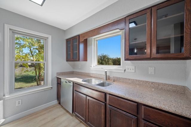 kitchen featuring light stone counters, stainless steel dishwasher, sink, light wood-type flooring, and dark brown cabinetry