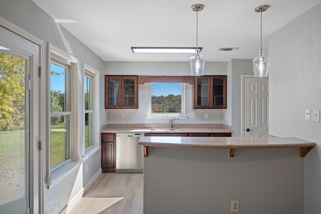 kitchen featuring a breakfast bar area, kitchen peninsula, sink, light hardwood / wood-style flooring, and stainless steel dishwasher