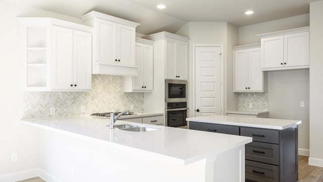 kitchen with sink, stainless steel appliances, a kitchen island, hardwood / wood-style floors, and white cabinets