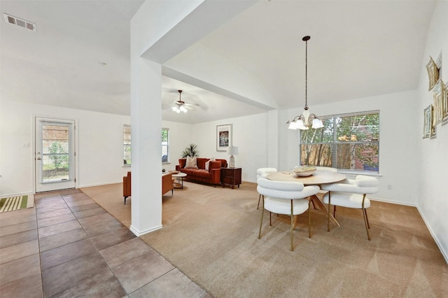 carpeted dining room featuring ceiling fan with notable chandelier, a wealth of natural light, and vaulted ceiling