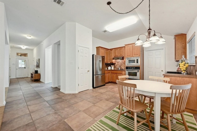 kitchen featuring stainless steel appliances, an inviting chandelier, light tile patterned floors, tasteful backsplash, and pendant lighting