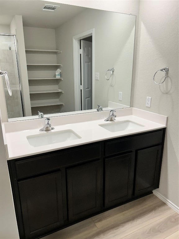 bathroom with hardwood / wood-style floors, a shower with shower door, and vanity