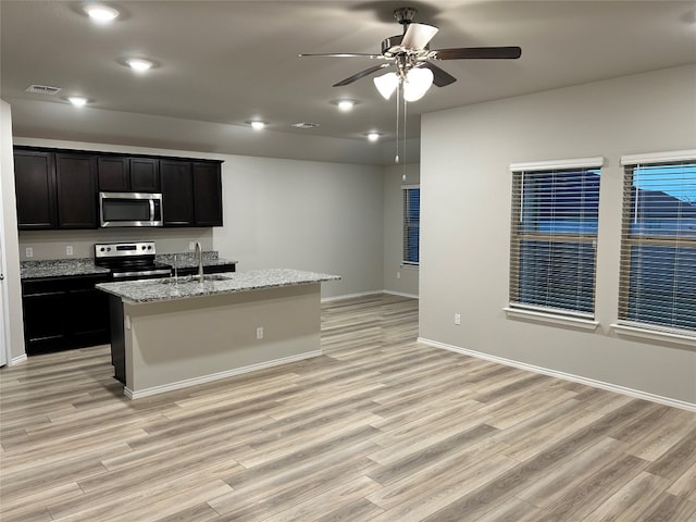 kitchen with a center island with sink, stainless steel appliances, sink, and light hardwood / wood-style flooring