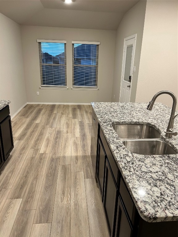 kitchen with sink, light wood-type flooring, and light stone counters