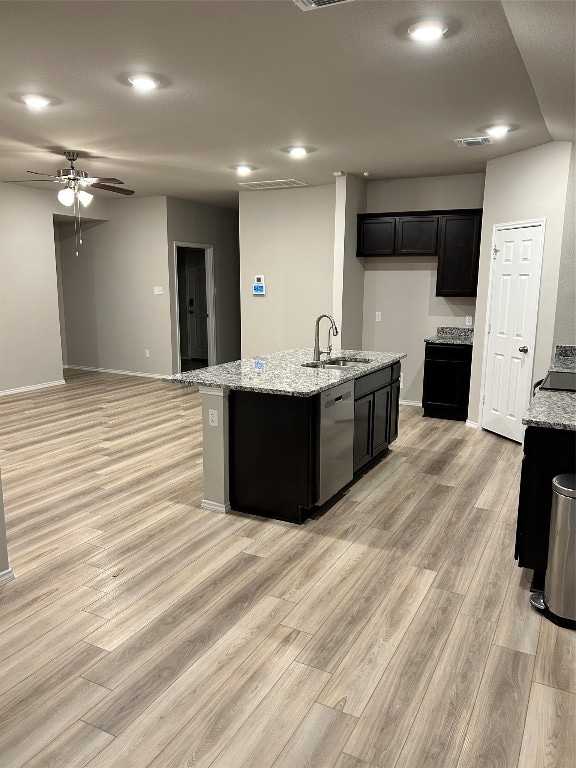 kitchen featuring stainless steel dishwasher, sink, light hardwood / wood-style floors, and a kitchen island with sink