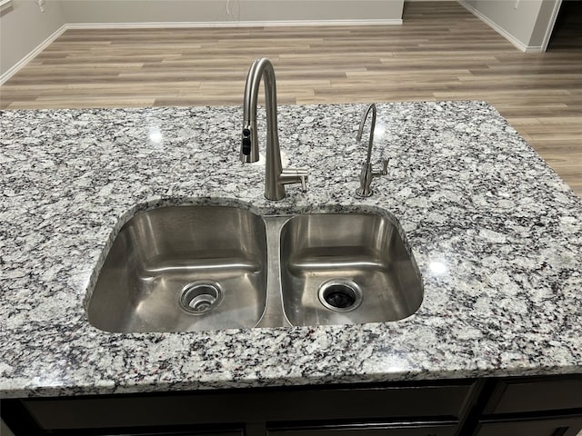 interior details featuring hardwood / wood-style floors, sink, and stone countertops