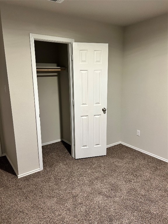 unfurnished bedroom featuring a closet and dark carpet