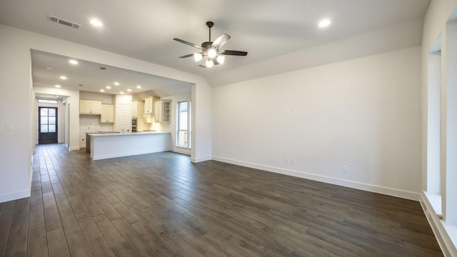 unfurnished living room featuring dark wood-type flooring and ceiling fan