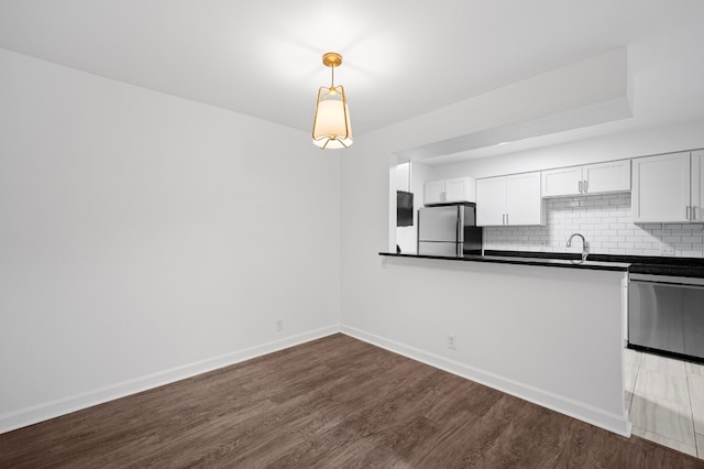 kitchen featuring dark hardwood / wood-style flooring, white cabinetry, pendant lighting, and stainless steel appliances