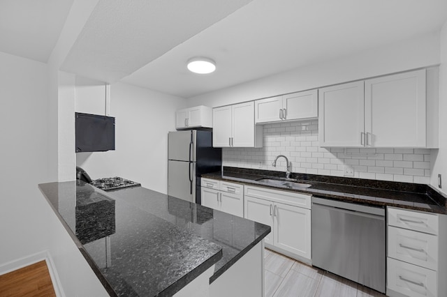 kitchen featuring tasteful backsplash, stainless steel appliances, dark stone counters, sink, and white cabinets