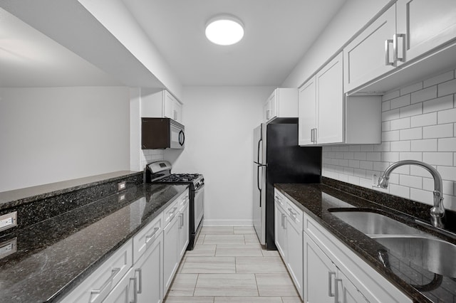 kitchen with dark stone counters, white cabinetry, sink, and black appliances