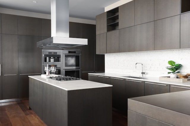 kitchen with sink, appliances with stainless steel finishes, wall chimney exhaust hood, a kitchen island, and dark wood-type flooring