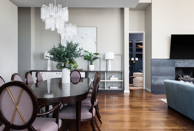 dining space with a tiled fireplace, dark wood-type flooring, and a notable chandelier