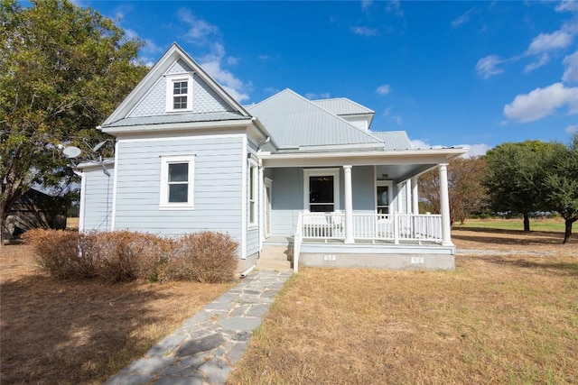 view of front of home with metal roof, a porch, and a front yard