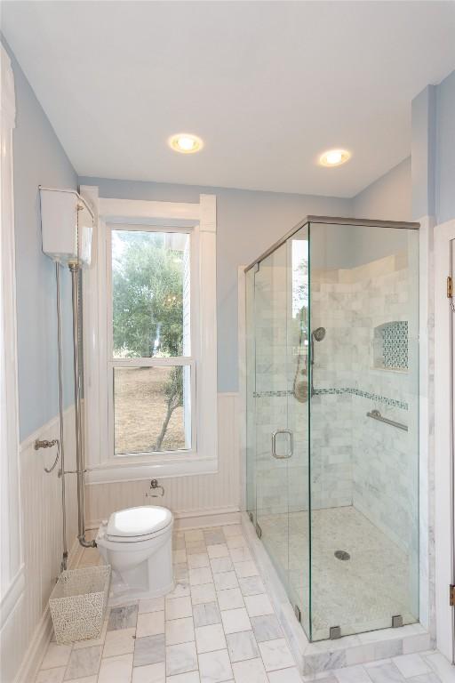 bathroom with a shower stall and wainscoting