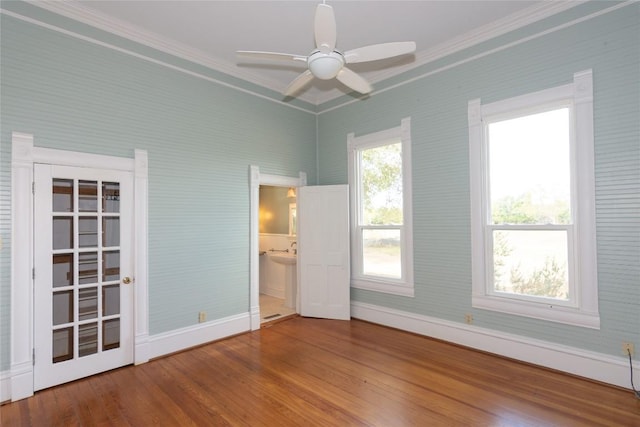 spare room with ceiling fan, crown molding, baseboards, and wood finished floors