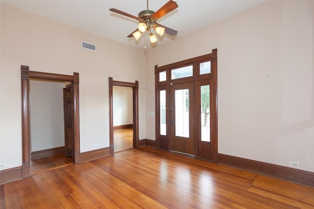 foyer with a ceiling fan, hardwood / wood-style flooring, visible vents, and baseboards