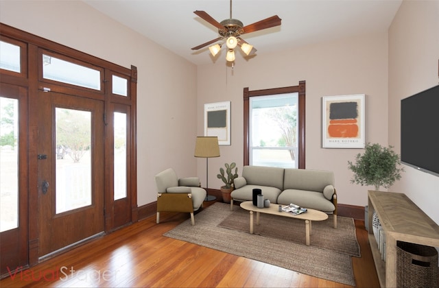 living area featuring light wood finished floors, ceiling fan, and baseboards