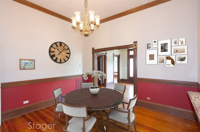 dining space with ornamental molding, an inviting chandelier, baseboards, and wood finished floors