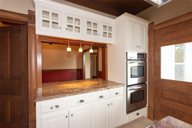 kitchen with white cabinets, double oven, glass insert cabinets, and light stone countertops