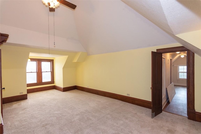 bonus room featuring vaulted ceiling, a textured ceiling, carpet flooring, and baseboards