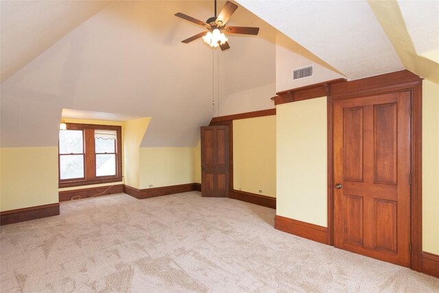 additional living space featuring ceiling fan, light colored carpet, visible vents, baseboards, and vaulted ceiling