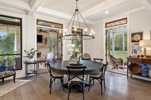 dining room featuring a fireplace, ornamental molding, ceiling fan with notable chandelier, and dark wood-type flooring