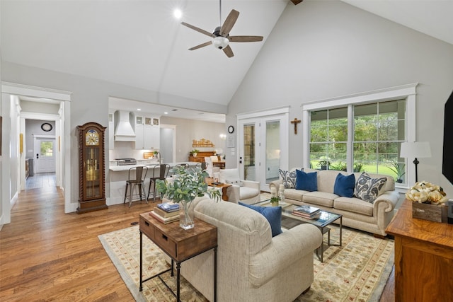 living room with french doors, light hardwood / wood-style floors, high vaulted ceiling, and ceiling fan