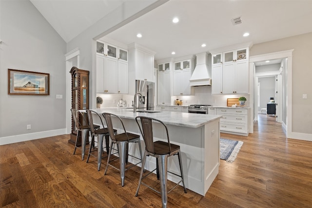 kitchen with white cabinetry, dark hardwood / wood-style floors, lofted ceiling, a center island with sink, and custom range hood