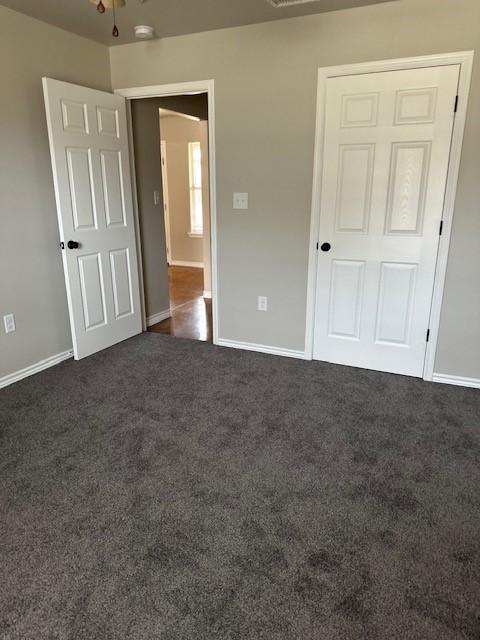 unfurnished bedroom with dark colored carpet