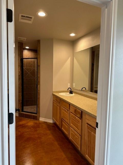 bathroom featuring a shower with door and vanity