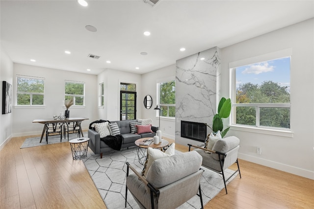 living room featuring light wood-type flooring, plenty of natural light, and a fireplace