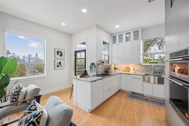 1310 S 1st St Unit 300, Austin, TX 78704 - kitchen featuring double oven, black electric cooktop, white cabinets, light wood finished floors, and recessed lighting