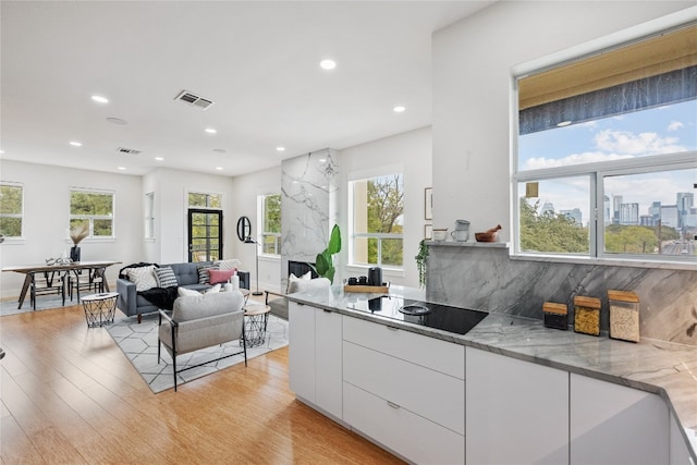 kitchen featuring white cabinetry, a wealth of natural light, black electric cooktop, and light stone counters