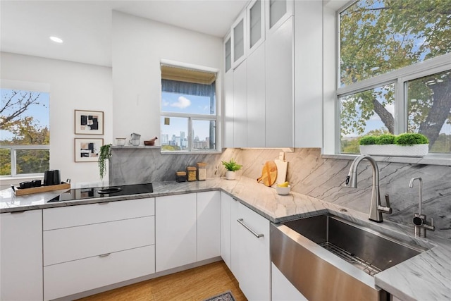1310 S 1st St Unit 300, Austin, TX 78704 - kitchen with black electric cooktop, healthy amount of natural light, light stone countertops, tasteful backsplash, and recessed lighting