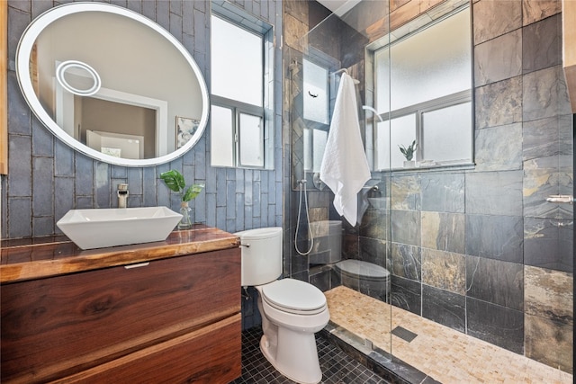 bathroom featuring plenty of natural light, toilet, a tile shower, and tile walls