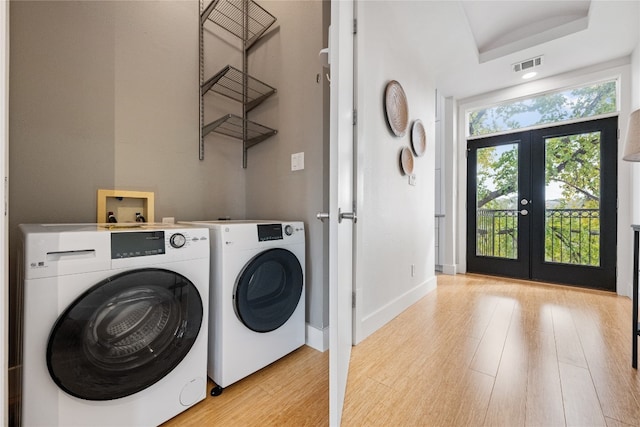 washroom featuring french doors, light hardwood / wood-style flooring, and washing machine and clothes dryer